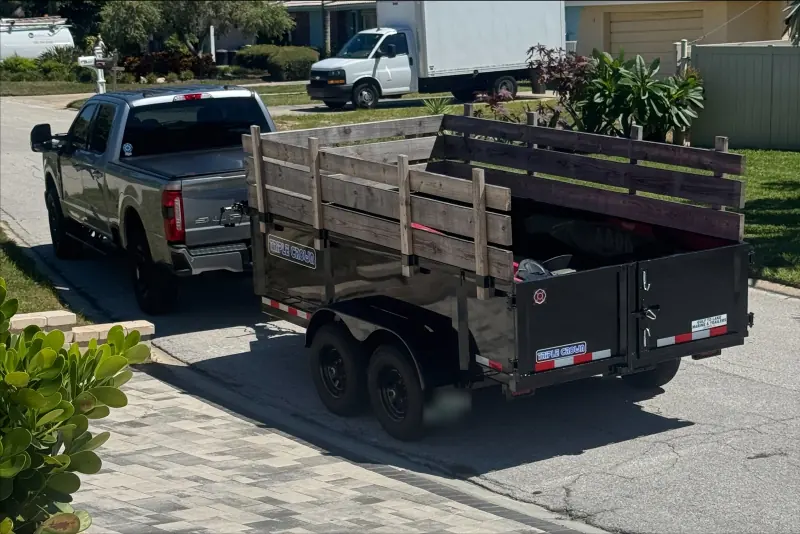 On Scene pickup towing a trailer with wood side extensions on a residential street